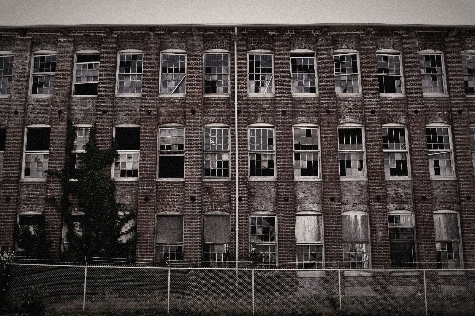 Brick factory with broken windows behind a fence